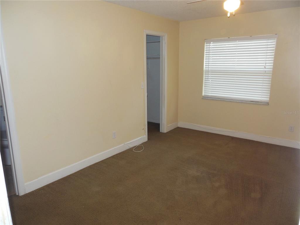 An empty bedroom with beige walls, brown carpet, a window with blinds, and a closet — 213 BUTTONWOOD AVENUE, WINTER SPRINGS, FL