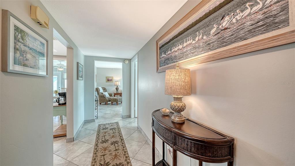 A hallway with tile floors, a console table, and wall art leads to an adjacent room — 2657 RIVERBLUFF PARKWAY UNIT V122, SARASOTA, FL