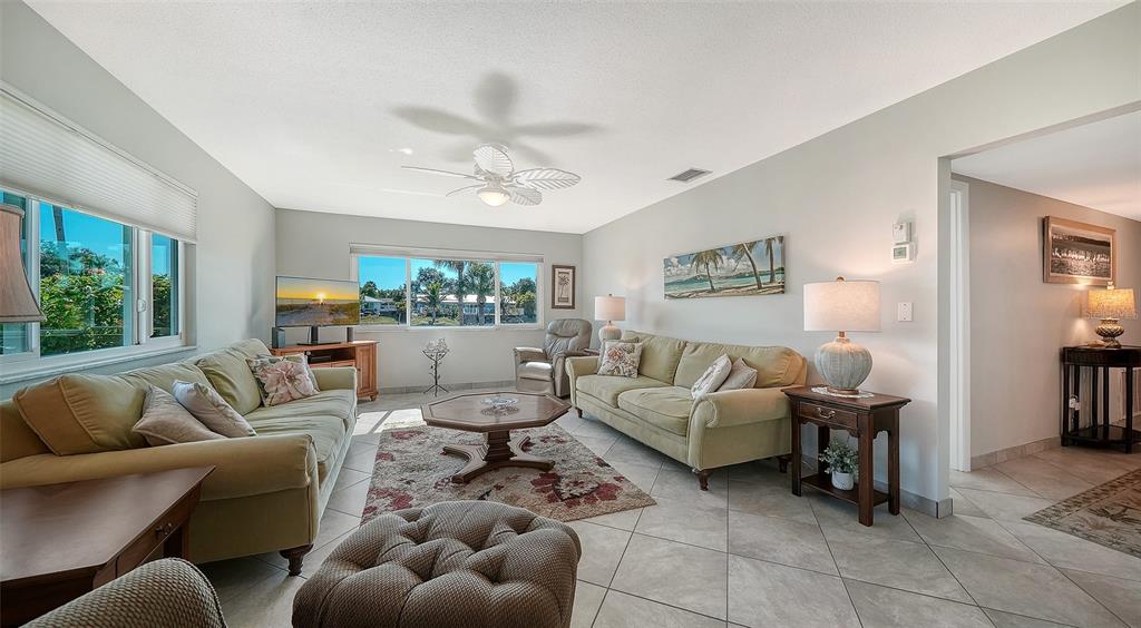 A living room features two beige sofas, a central coffee table, and tile flooring — 2657 RIVERBLUFF PARKWAY UNIT V122, SARASOTA, FL