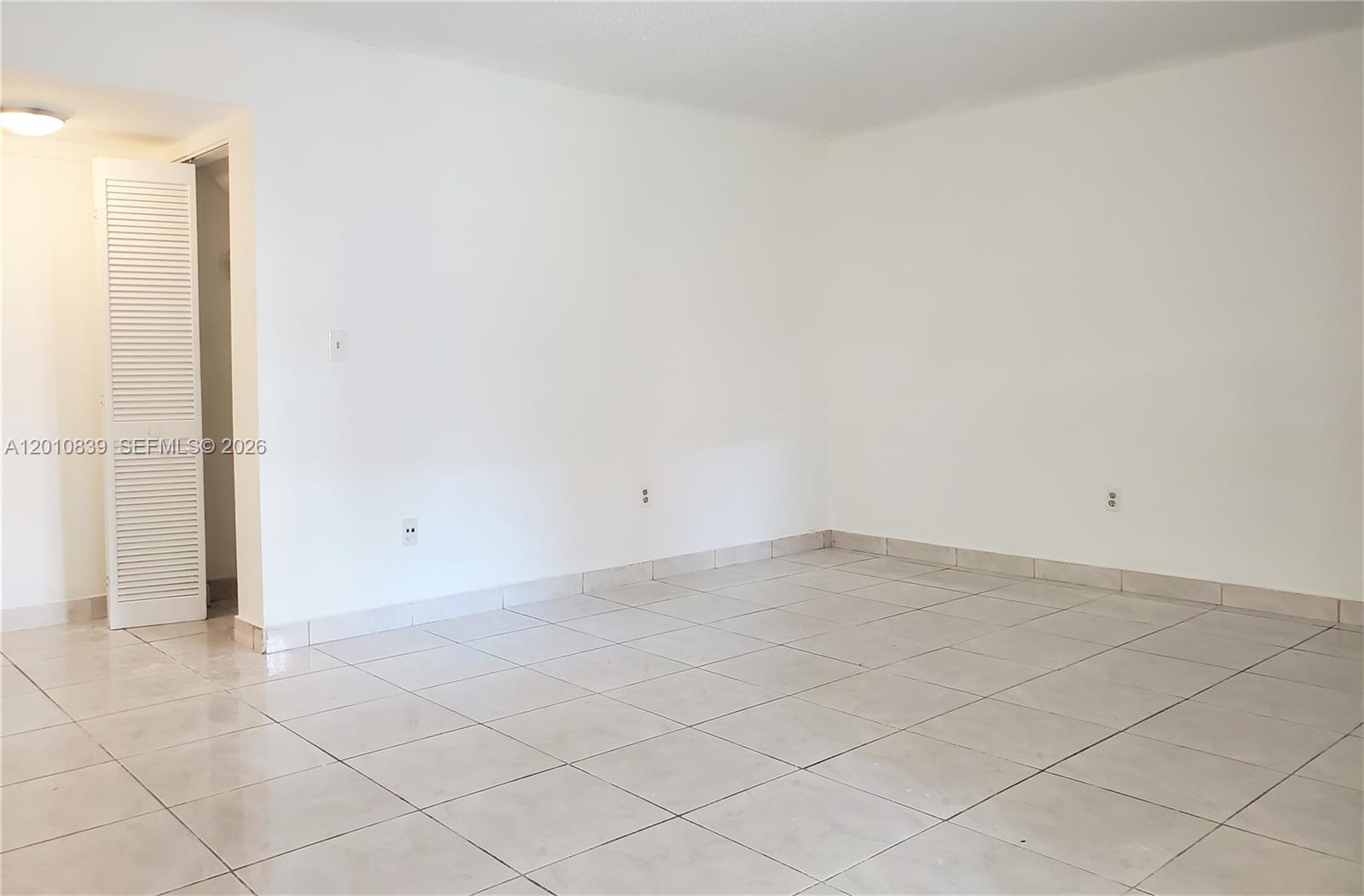 An empty room features white walls, light-colored tile flooring, and a white louvered closet door — 10020 NW 9th St Cir # 102, Miami FL 33172, MIAMI, FL
