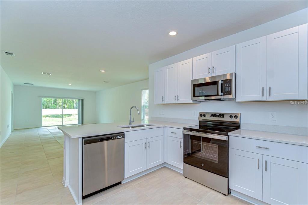 A kitchen with white cabinets, stainless steel appliances, and a peninsula island — 13341 TROPICAL BREEZE WAY, HUDSON, FL