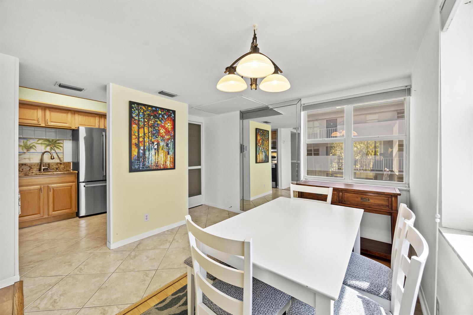 A dining area with a white table and chairs sits adjacent to a kitchen with stainless appliances — 1820 New Palm Way # 308, Boynton Beach FL 33435, BOYNTON BEACH, FL