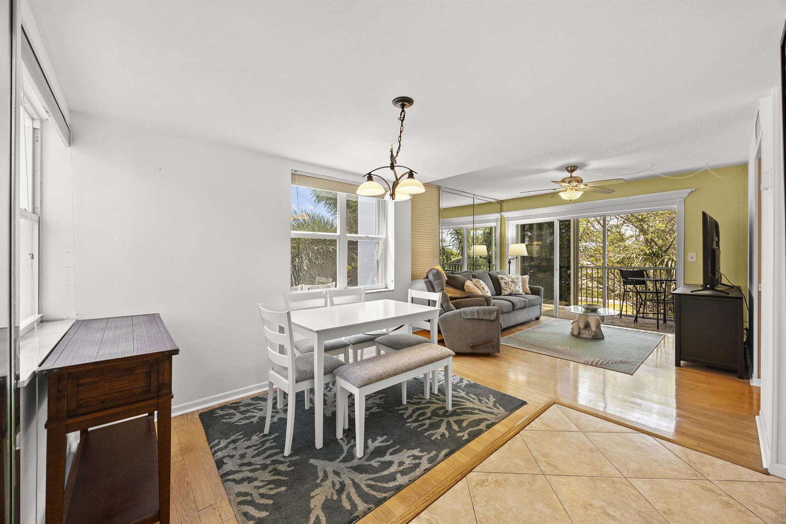 A dining area with a white table and bench sits next to a living room — 1820 New Palm Way # 308, Boynton Beach FL 33435, BOYNTON BEACH, FL