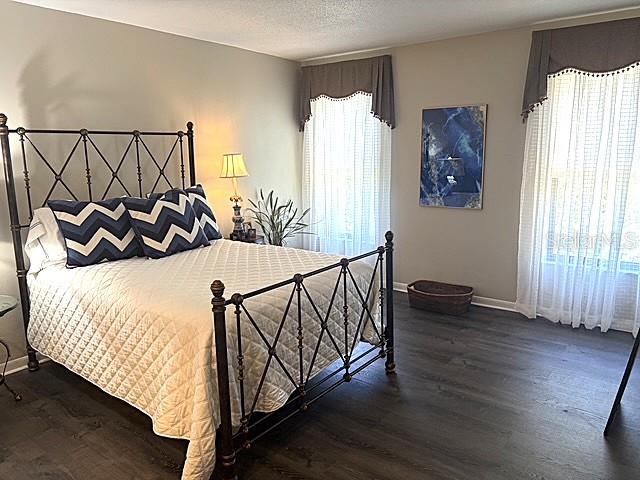A bedroom features a dark metal bed frame, chevron pillows, and wood-look flooring — 3078 EASTLAND BOULEVARD UNIT 307, CLEARWATER, FL