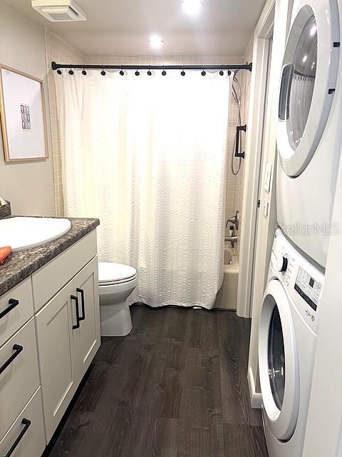 A bathroom features a white shower curtain, a toilet, a vanity, and a stacked laundry unit — 3078 EASTLAND BOULEVARD UNIT 307, CLEARWATER, FL