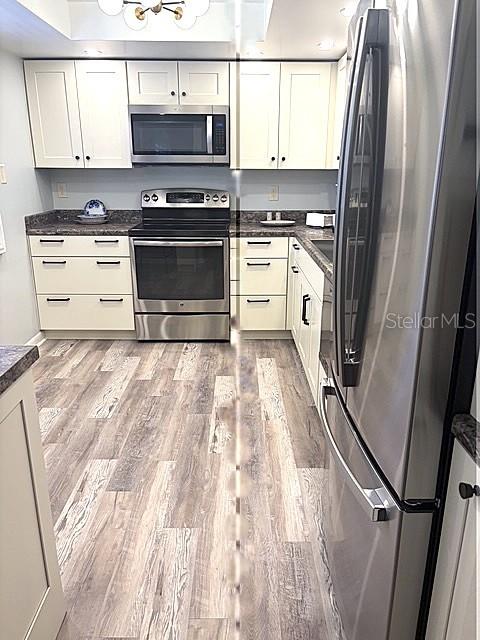 A kitchen features white cabinets, stainless steel appliances, and wood-look flooring — 3078 EASTLAND BOULEVARD UNIT 307, CLEARWATER, FL