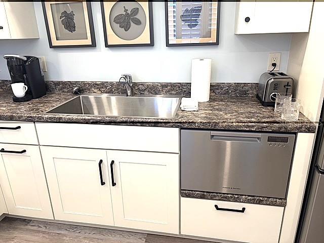 A kitchen features white cabinets, a stainless steel sink, and a dishwasher under granite countertops — 3078 EASTLAND BOULEVARD UNIT 307, CLEARWATER, FL