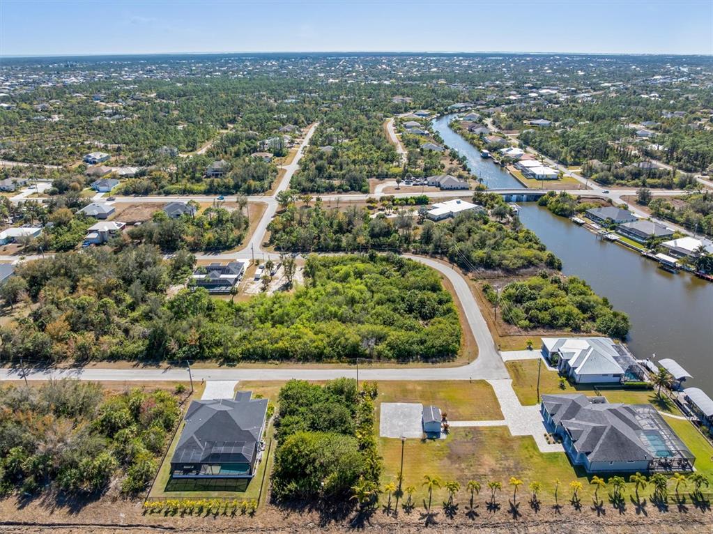 An aerial view shows a residential neighborhood with houses, a canal, and vacant lots — 14303 CANDO AVENUE, PORT CHARLOTTE, FL