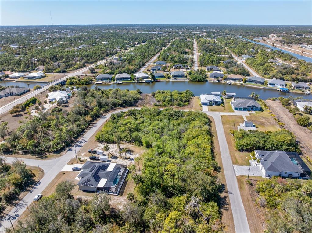 An aerial view shows a vacant lot surrounded by residential homes and a canal — 14303 CANDO AVENUE, PORT CHARLOTTE, FL