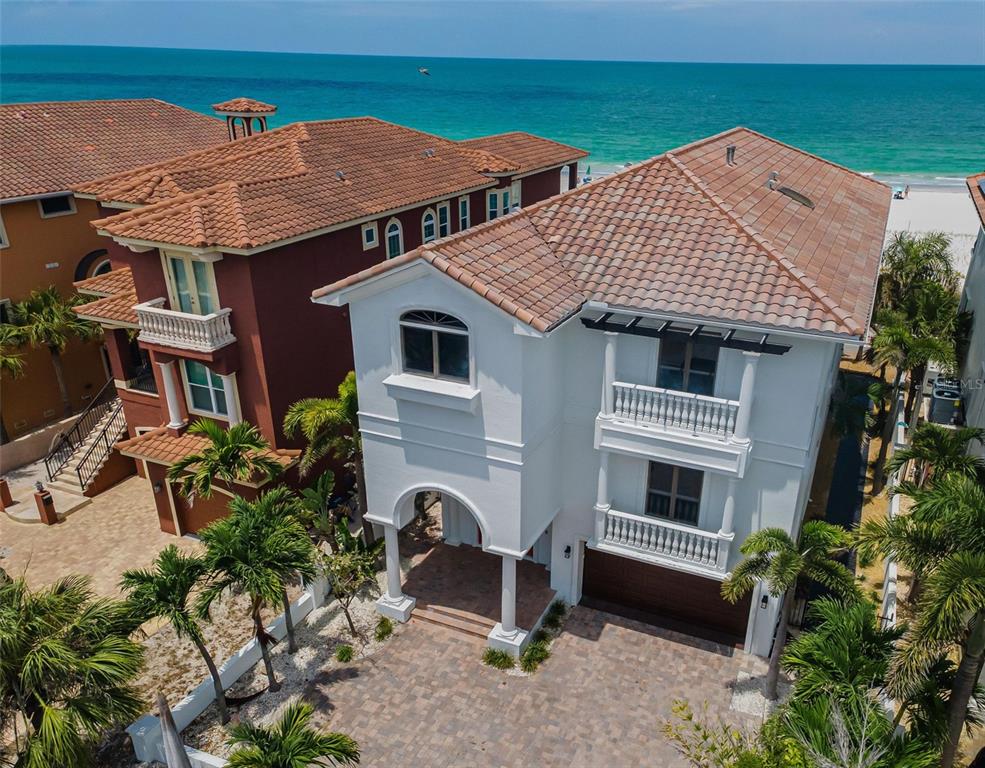 An aerial view shows two multi-story houses with tiled roofs situated along a sandy beach — 9550 W GULF BOULEVARD, TREASURE ISLAND, FL