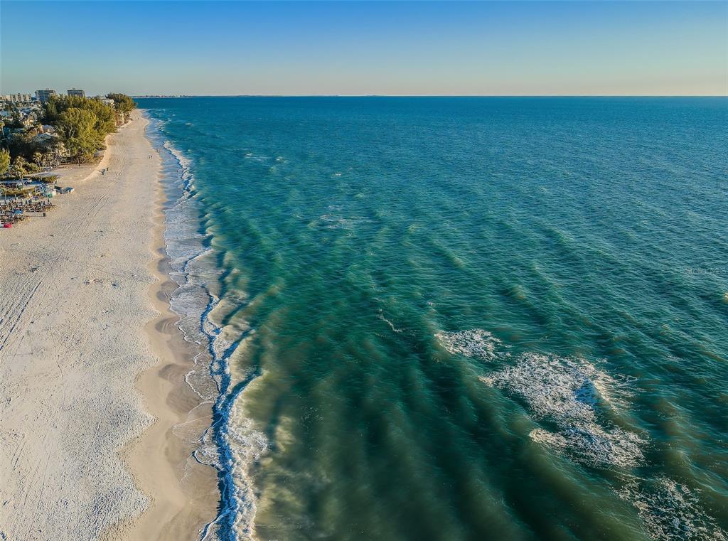 An aerial view of a sandy beach meeting the turquoise ocean under a clear sky — 9550 W GULF BOULEVARD, TREASURE ISLAND, FL