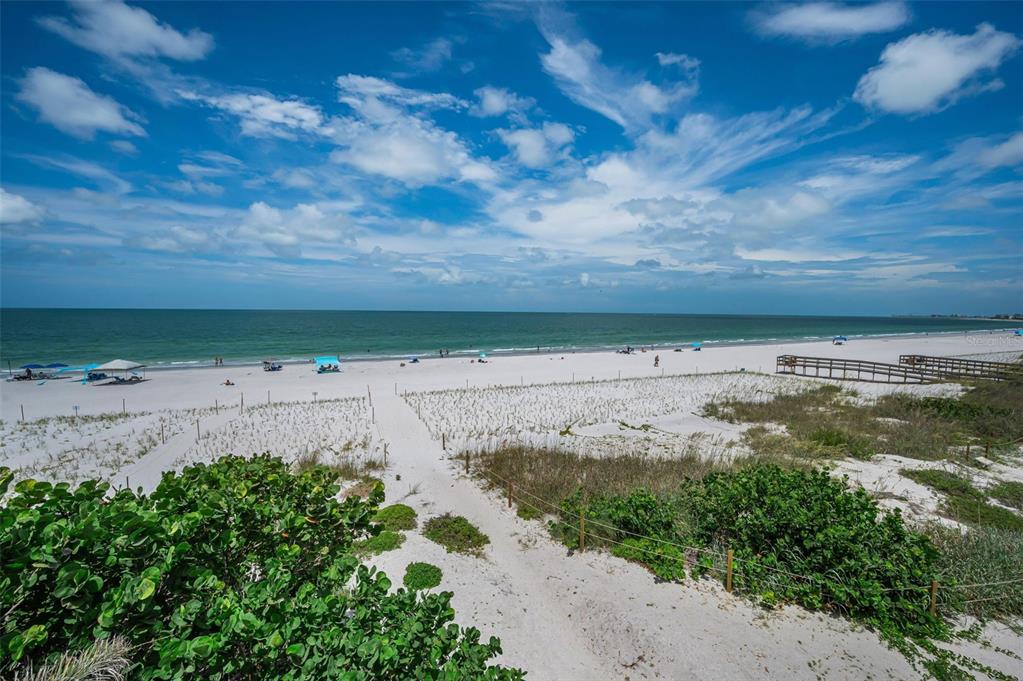 A sandy path leads through dunes to a wide beach with the ocean beyond — 9550 W GULF BOULEVARD, TREASURE ISLAND, FL
