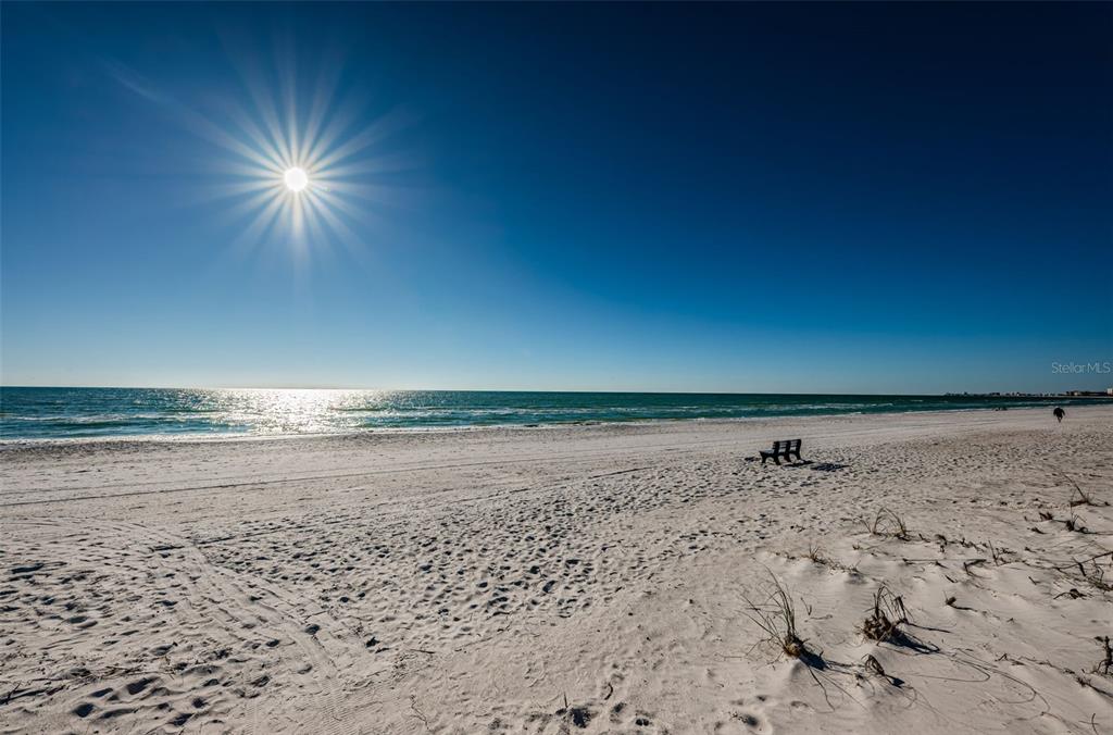 A bright sun shines over a wide, white sand beach meeting the ocean — 9550 W GULF BOULEVARD, TREASURE ISLAND, FL