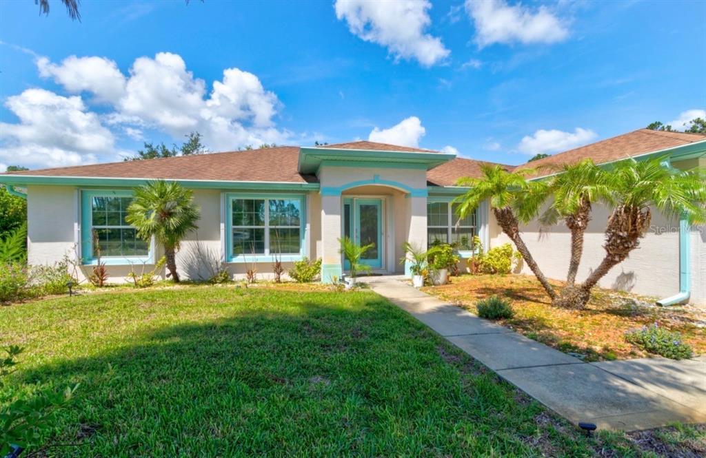 A single-story house with a light-colored stucco exterior, teal trim, and a front walkway — 10 LLOSHIRE PATH, PALM COAST, FL