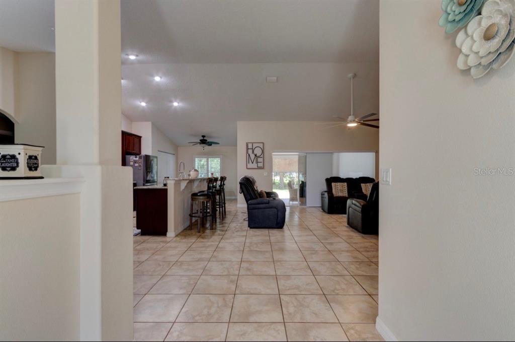 An open-concept living area features a kitchen with a breakfast bar and tile flooring — 10 LLOSHIRE PATH, PALM COAST, FL