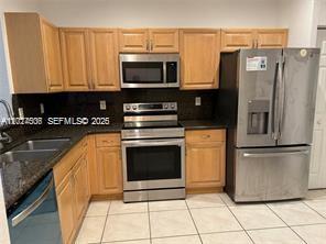 A kitchen features light wood cabinets, stainless steel appliances, and dark granite countertops — 3907 Tree Top Dr # 3907, Weston FL 33332, WESTON, FL