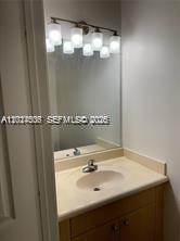 A bathroom vanity features a light wood cabinet, a white countertop, and a multi-light fixture — 3907 Tree Top Dr # 3907, Weston FL 33332, WESTON, FL