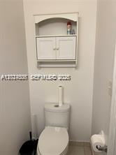 A white bathroom features a toilet, a wall-mounted cabinet with open shelving, and a towel bar — 3907 Tree Top Dr # 3907, Weston FL 33332, WESTON, FL