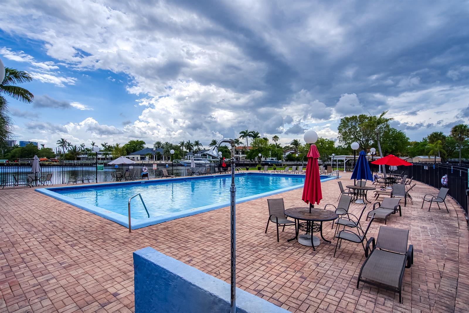 A rectangular swimming pool is surrounded by a brick patio with lounge chairs and umbrellas — 2000 Atlantic Shores Boulevard # 410, Hallandale Beach FL 33009, HALLANDALE BEACH, FL