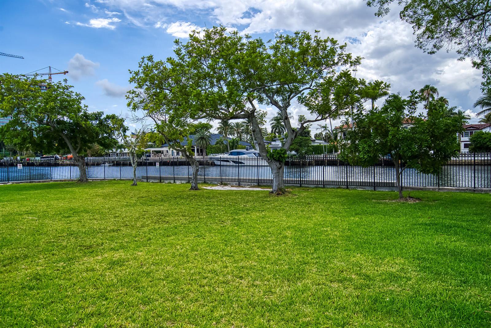A grassy lawn with several trees sits in front of a black metal fence — 2000 Atlantic Shores Boulevard # 410, Hallandale Beach FL 33009, HALLANDALE BEACH, FL