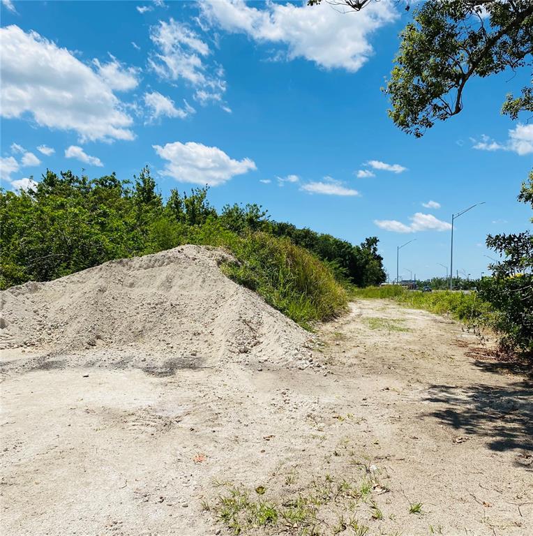 A large pile of dirt sits on a vacant, unpaved lot under a blue sky — US HWY 27, HAINES CITY, FL