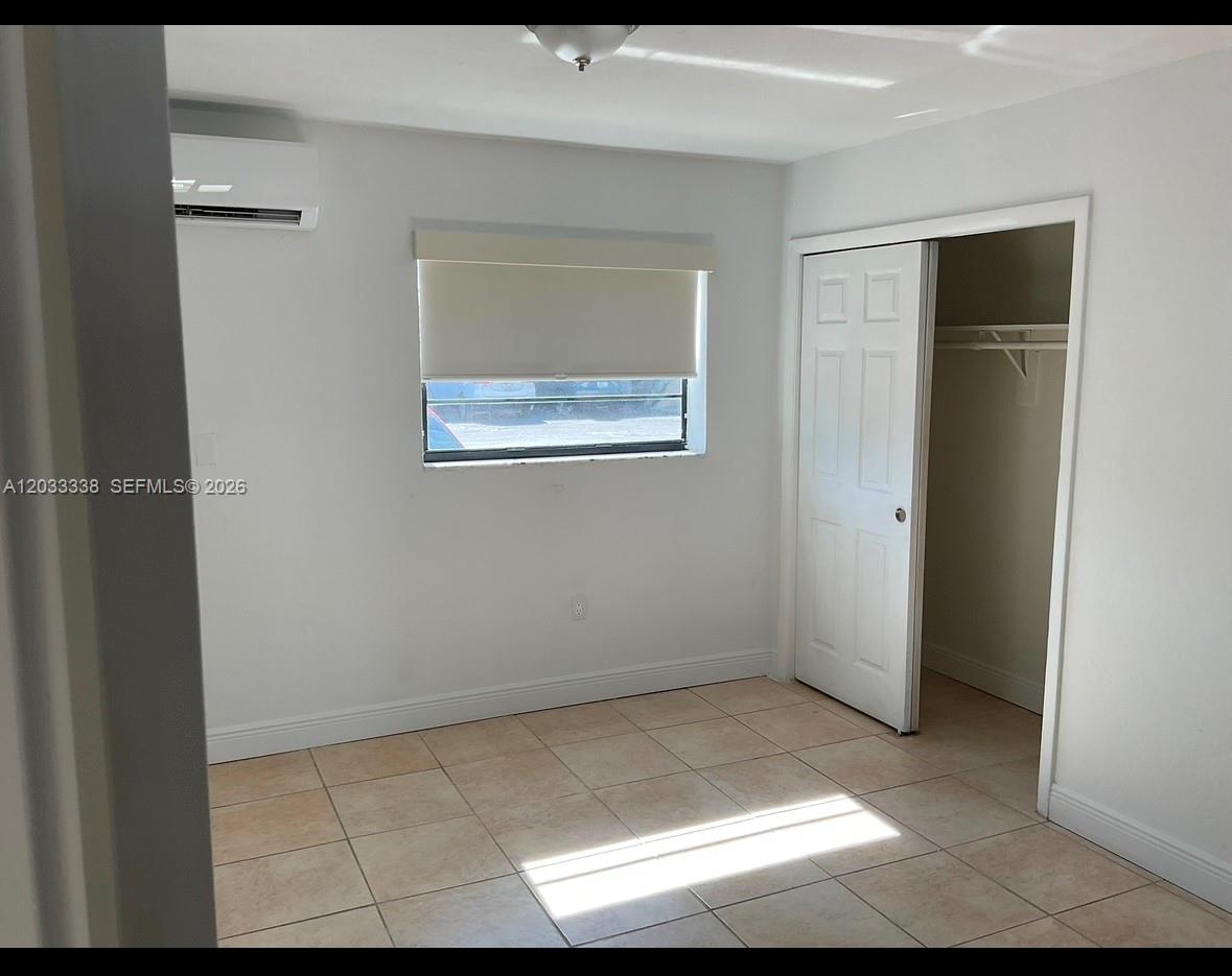 A bedroom with light-colored tile flooring, a window with a roller shade, and a closet — 6780 SW 44th St # 2, Miami FL 33155, MIAMI, FL