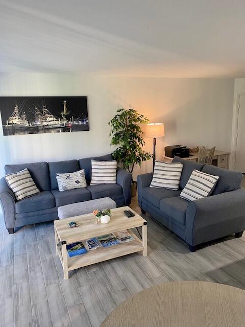 A living room features two blue sofas, a wooden coffee table, and a nautical wall print — 1605 S Us Highway 1 # 106, Jupiter FL 33477, JUPITER, FL