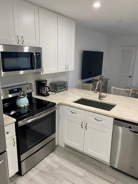 A modern kitchen features white cabinets, stainless steel appliances, and a light-colored stone countertop — 1605 S Us Highway 1 # 106, Jupiter FL 33477, JUPITER, FL