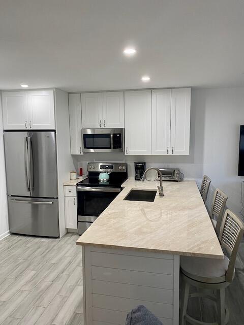 A modern kitchen features white cabinetry, stainless steel appliances, and a light-toned stone island countertop — 1605 S Us Highway 1 # 106, Jupiter FL 33477, JUPITER, FL