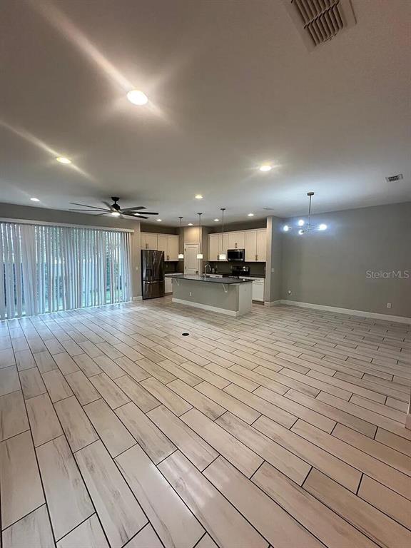 An open-concept kitchen and living area features light wood-look tile flooring and white cabinetry — 534 LAKE WILDMERE COVE, LONGWOOD, FL