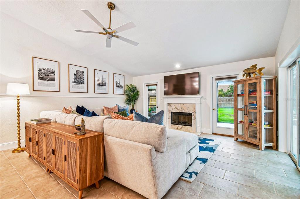 A living room features a sectional sofa, fireplace, ceiling fan, and a wooden display cabinet — 10503 NILE COURT, TAMPA, FL