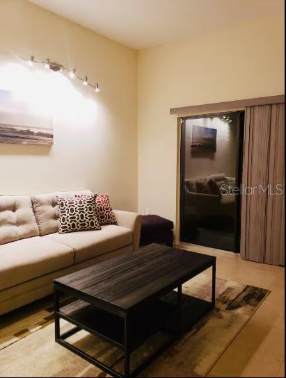 A living room features a beige sofa, a dark wood coffee table, and a sliding door — 701 S MADISON AVENUE UNIT 109, CLEARWATER, FL