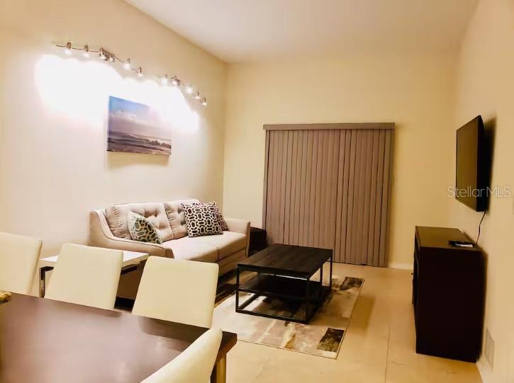 A living room features a beige sofa, a dark coffee table, and a wall-mounted television — 701 S MADISON AVENUE UNIT 109, CLEARWATER, FL