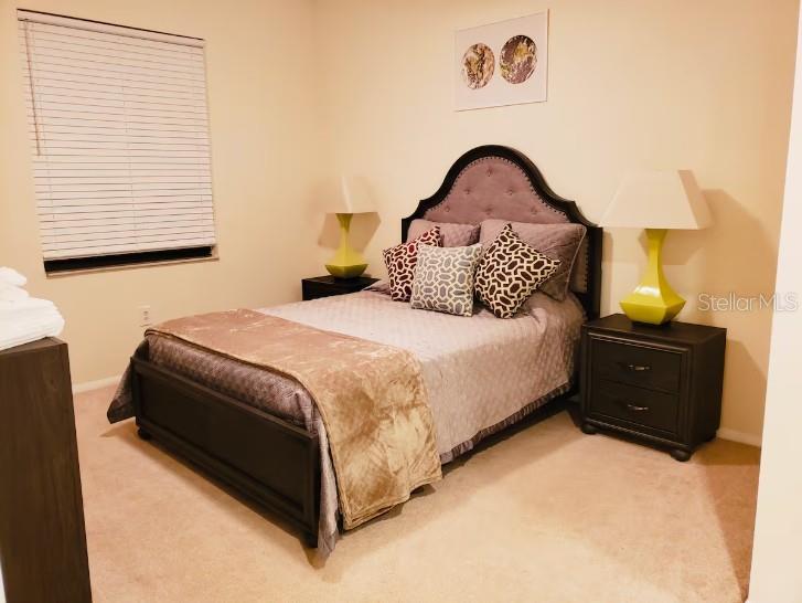 A bedroom features a bed with a tufted headboard, two nightstands, and matching table lamps — 701 S MADISON AVENUE UNIT 109, CLEARWATER, FL