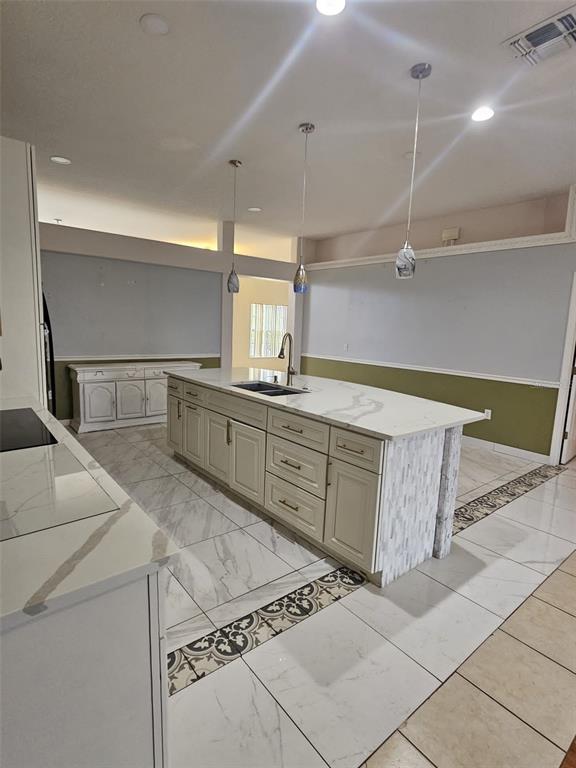 A kitchen features a large marble-topped island with pendant lighting and white cabinetry — 807 MASSY COURT, KISSIMMEE, FL