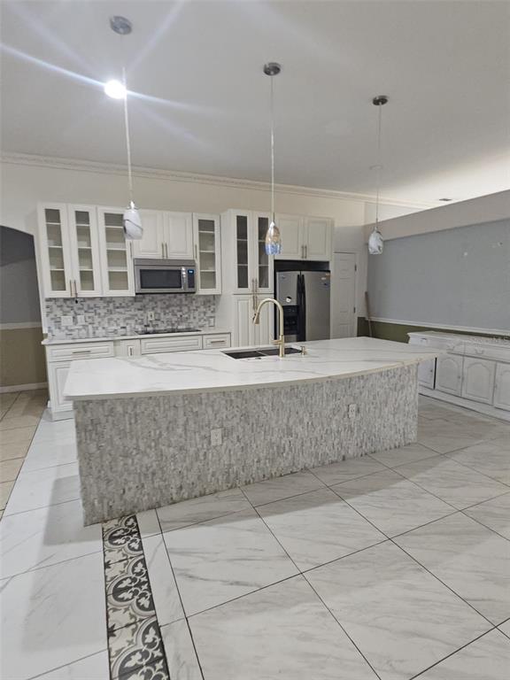 A kitchen features white cabinets, a large stone-topped island, and light-colored tile flooring — 807 MASSY COURT, KISSIMMEE, FL