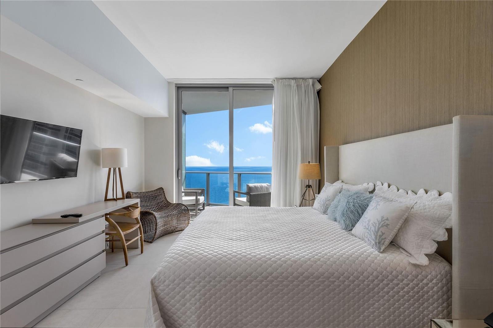 A bedroom with a king bed, desk, and sliding glass doors opening to an ocean view — 4111 S Ocean Drive, Hollywood FL 33019, HOLLYWOOD, FL