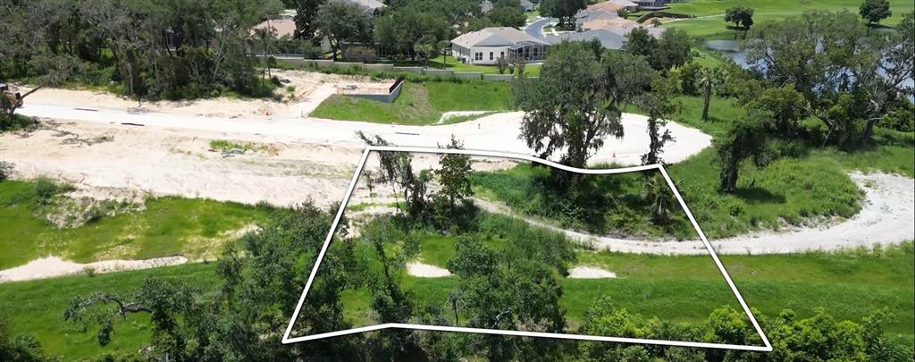 An aerial view shows a vacant, wooded residential lot outlined in white near a paved road — 141 TRANQUIL MIRROR LAKE COURT Lot 14, CLERMONT, FL