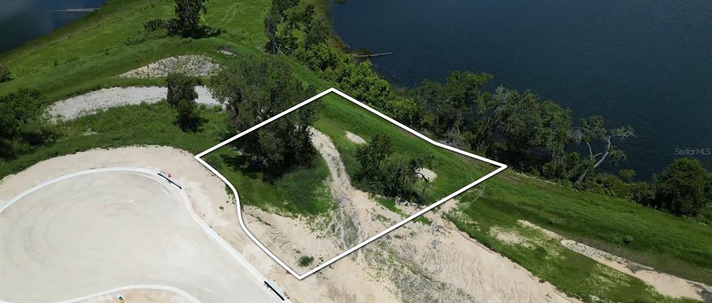 An aerial view shows a vacant, irregularly shaped residential lot bordering a lake — 141 TRANQUIL MIRROR LAKE COURT Lot 14, CLERMONT, FL