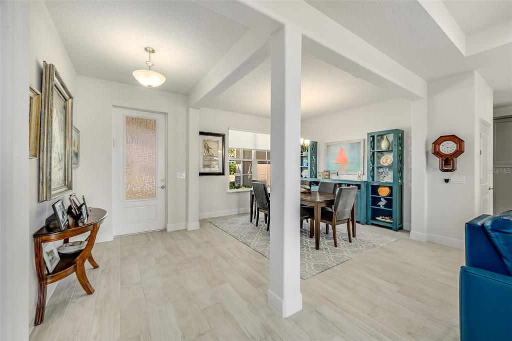 A bright entryway with light wood-look flooring leads into a dining area with a rug — 2003 KILLIAN DRIVE NE, PALM BAY, FL