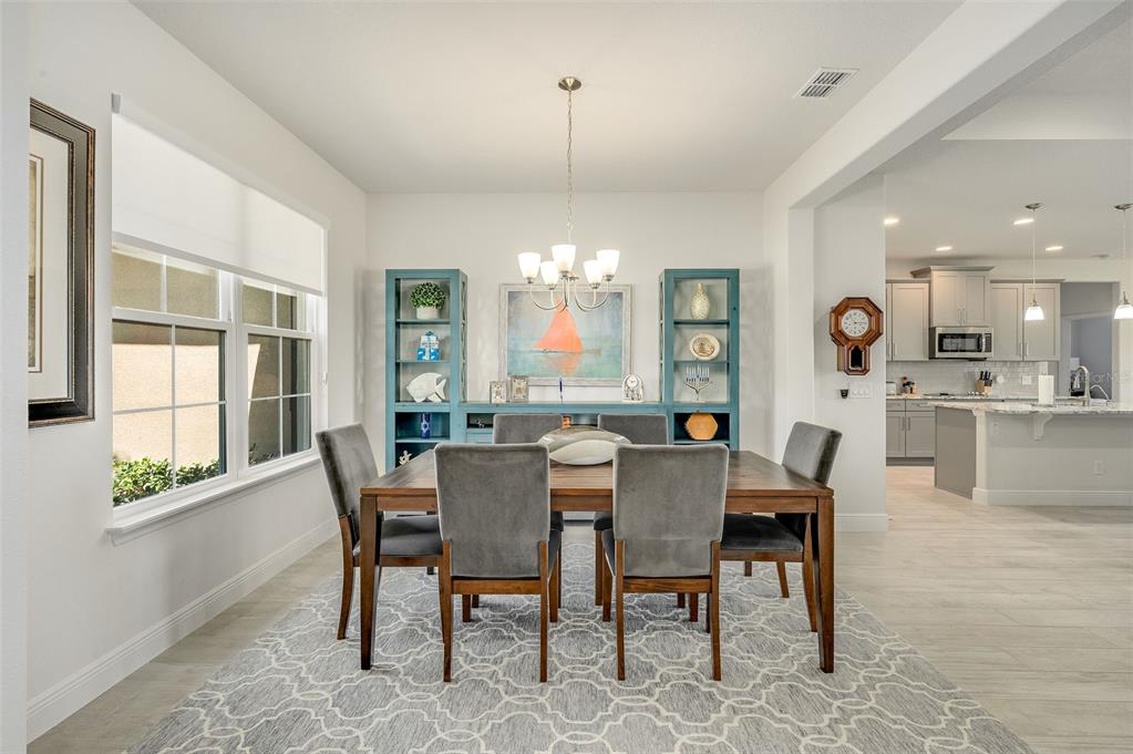 A dining room features a wooden table, six gray chairs, and blue shelving units — 2003 KILLIAN DRIVE NE, PALM BAY, FL