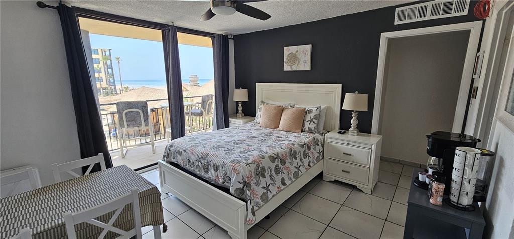 A bedroom features a queen bed, tile flooring, and a balcony overlooking the ocean — 2301 S ATLANTIC AVENUE UNIT 229, DAYTONA BEACH, FL