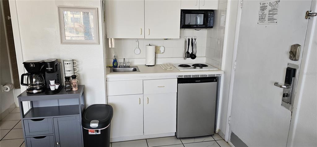 A small kitchenette features white cabinets, a sink, a stovetop, and a mini-fridge — 2301 S ATLANTIC AVENUE UNIT 229, DAYTONA BEACH, FL