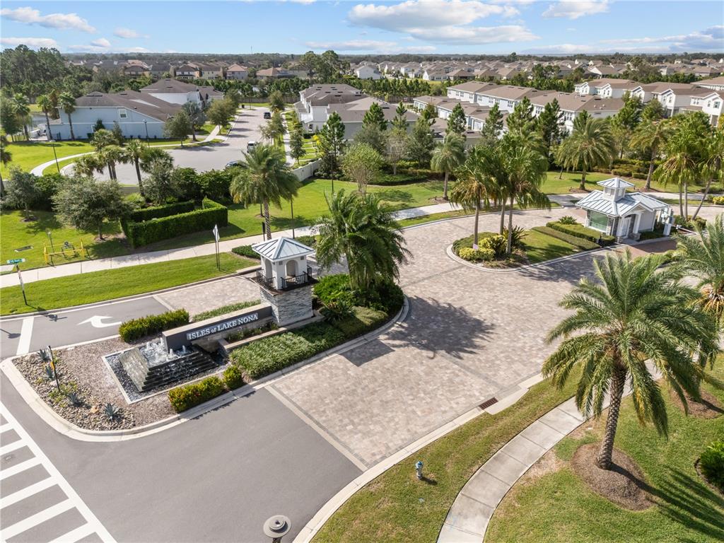 An aerial view shows the gated entrance of a residential community with a stone sign — 14514 ORCHID ISLAND DRIVE, ORLANDO, FL