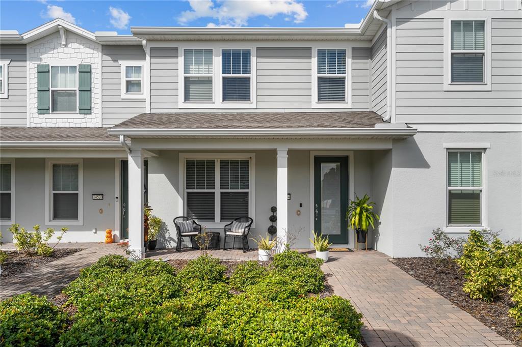A two-story townhouse exterior features gray siding, a covered front porch, and a brick walkway — 14514 ORCHID ISLAND DRIVE, ORLANDO, FL