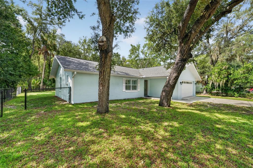 A light blue, single-story house with a garage and large trees in the front yard — 11108 W THOREAU PLACE, CRYSTAL RIVER, FL