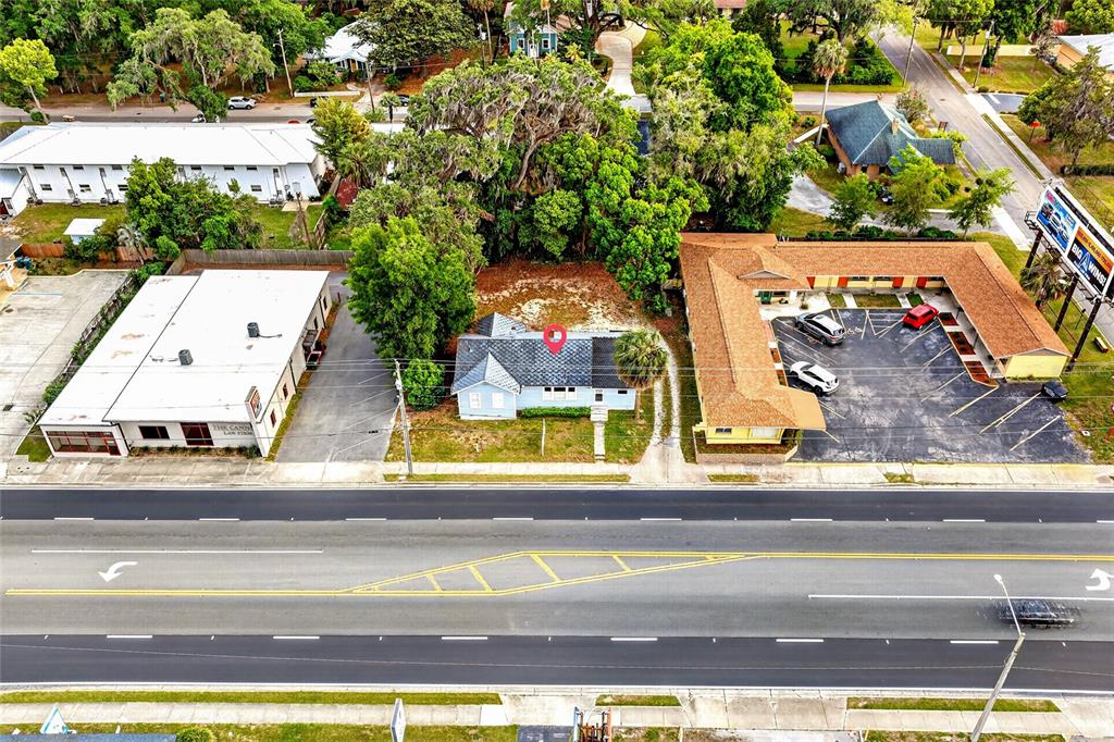 An aerial view shows a small house with a red pin situated between two commercial buildings — 1266 E SILVER SPRINGS BOULEVARD, OCALA, FL
