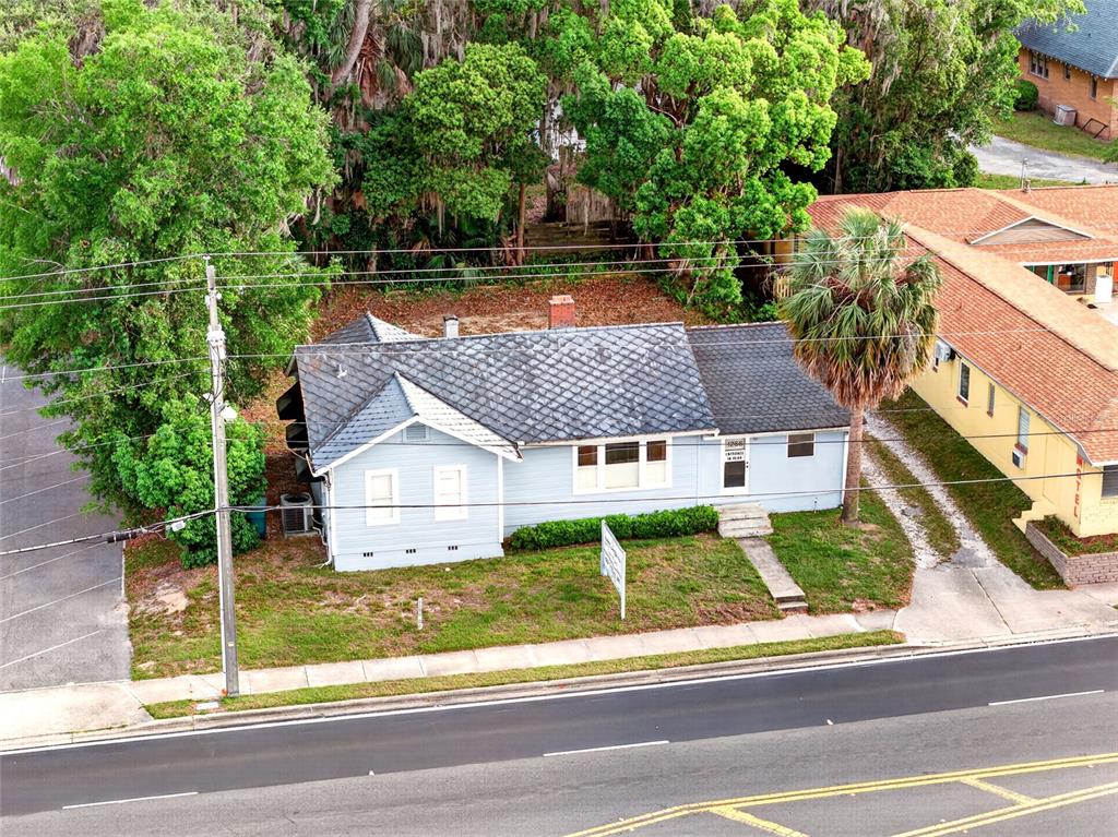 An aerial view shows a light blue house with a dark shingled roof and yard — 1266 E SILVER SPRINGS BOULEVARD, OCALA, FL