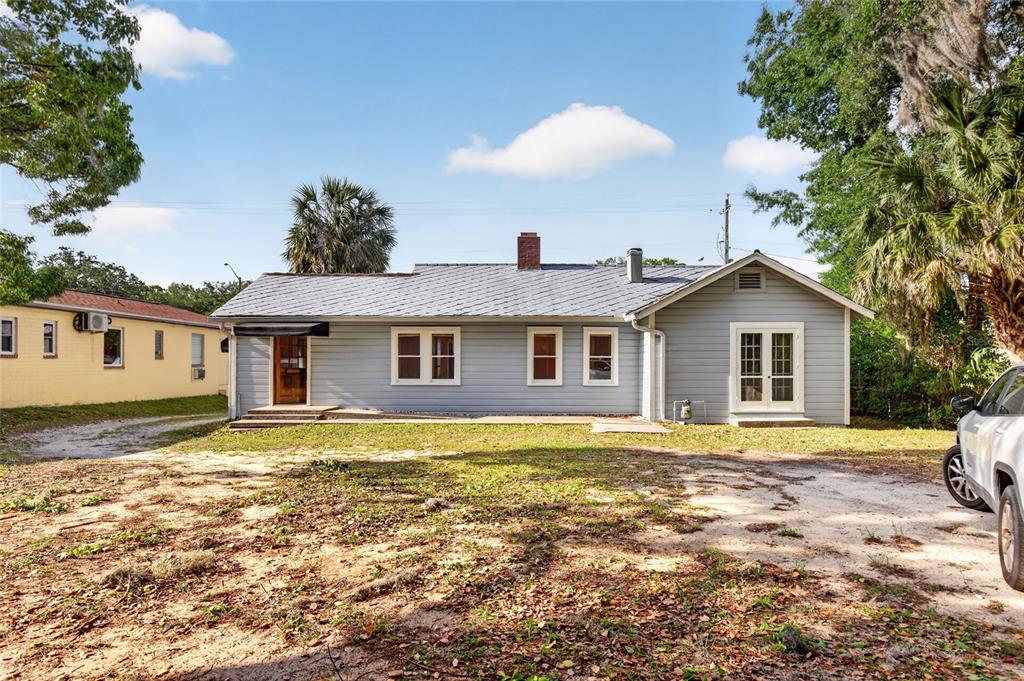 A light gray, single-story house with a metal roof and a dirt yard — 1266 E SILVER SPRINGS BOULEVARD, OCALA, FL