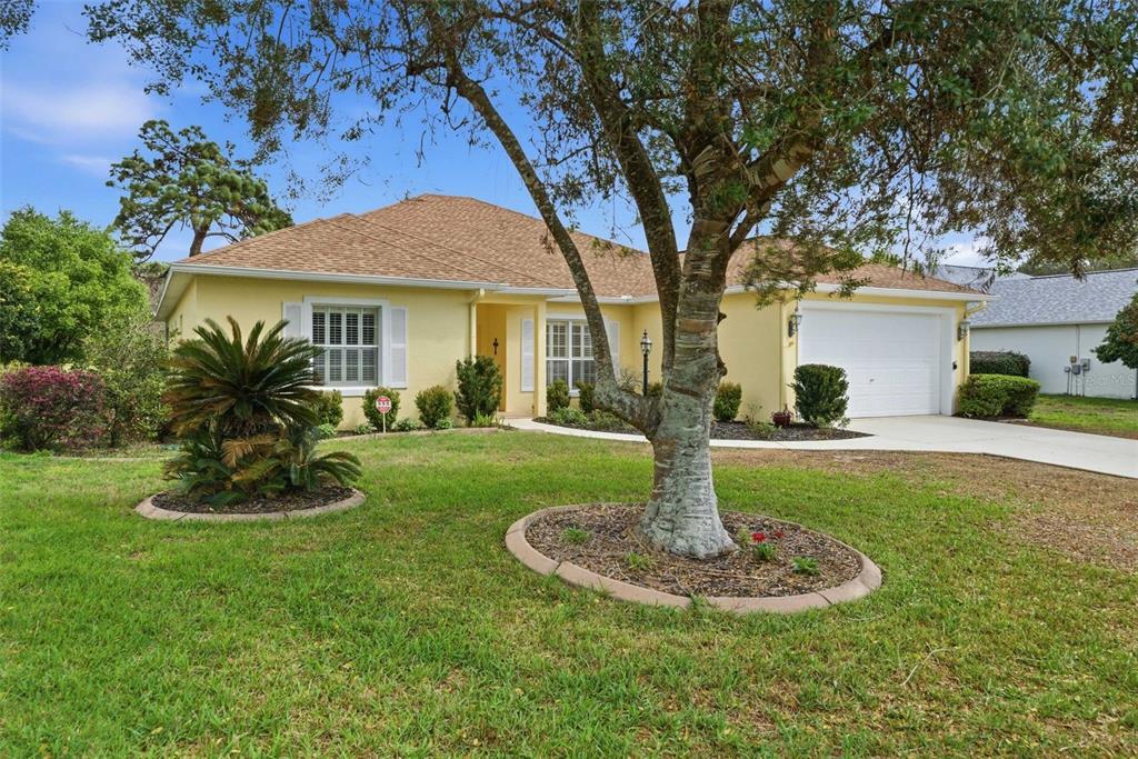 A yellow single-story house with a two-car garage and a large tree in the yard — 39 W AMALFI COURT, BEVERLY HILLS, FL